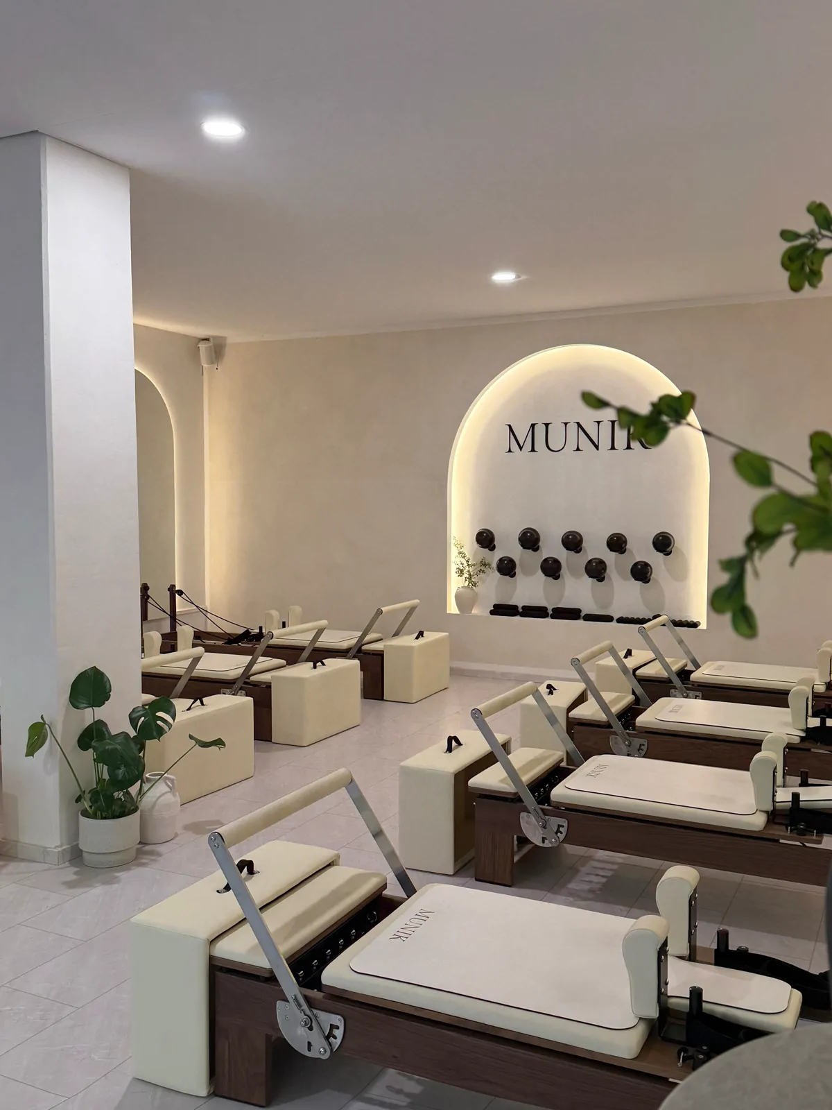Reformer Pilates Studio München – heller Trainingsraum mit beleuchtetem MUNIK-Logo und Reformern