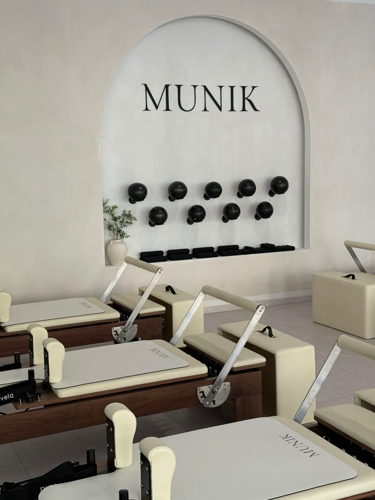 Reformer im MUNIK reformer studio München mit MUNIK-Wandlogo und Wandbällen